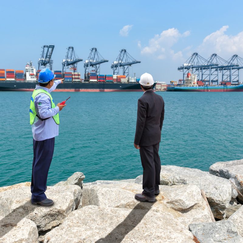 Engineer with his manager check for shipping the container box loading at harbor.
